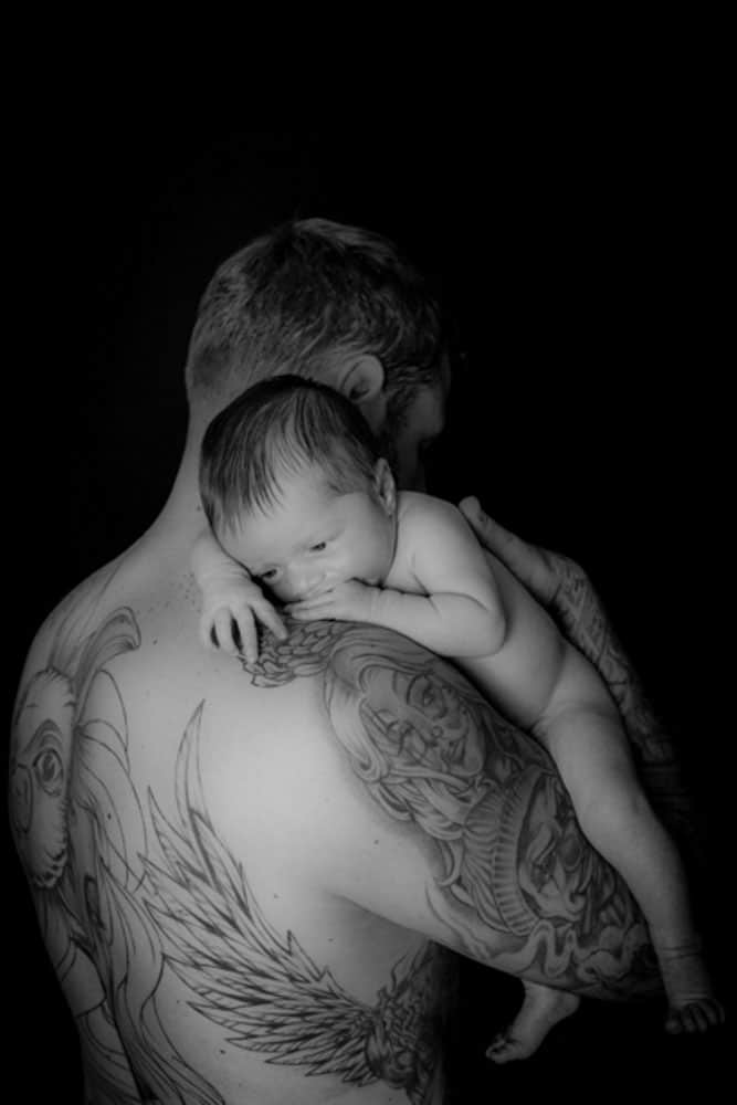 Tattooed father holding newborn baby skin to skin Birmingham