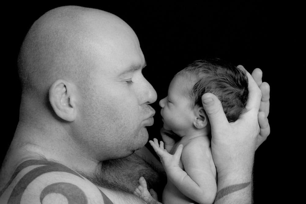 Parents kissing newborn baby black and white Birmingham