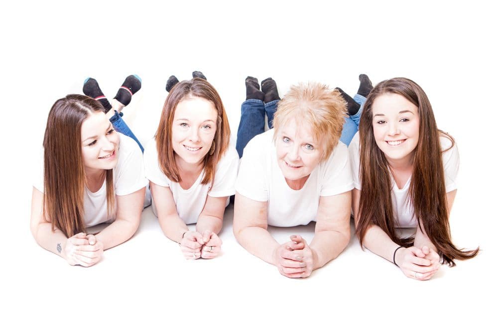 Four generation family portrait lying together on a white background during a Birmingham family photoshoot
