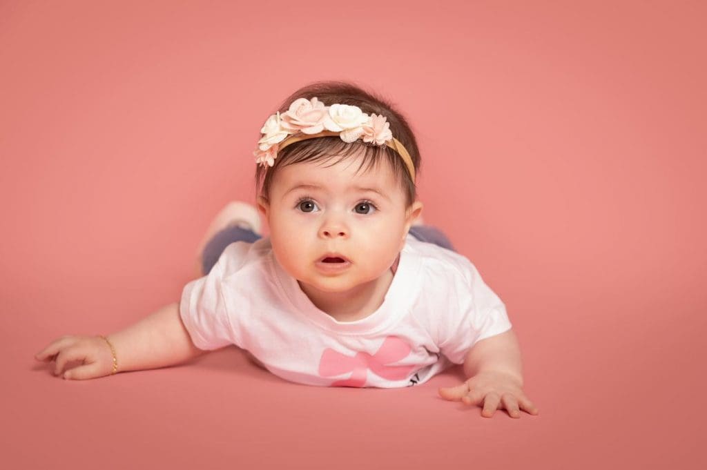 Baby girl lying on her tummy wearing a floral headband during a professional baby photoshoot in Birmingham.
