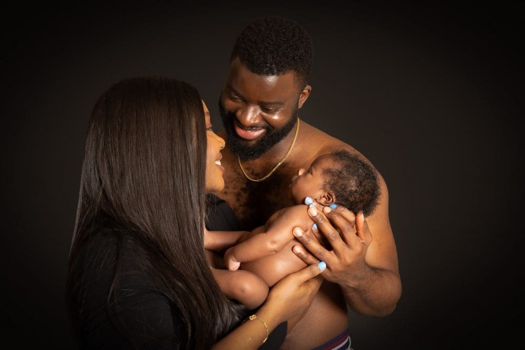 Parents smiling at newborn baby skin to skin Birmingham studio