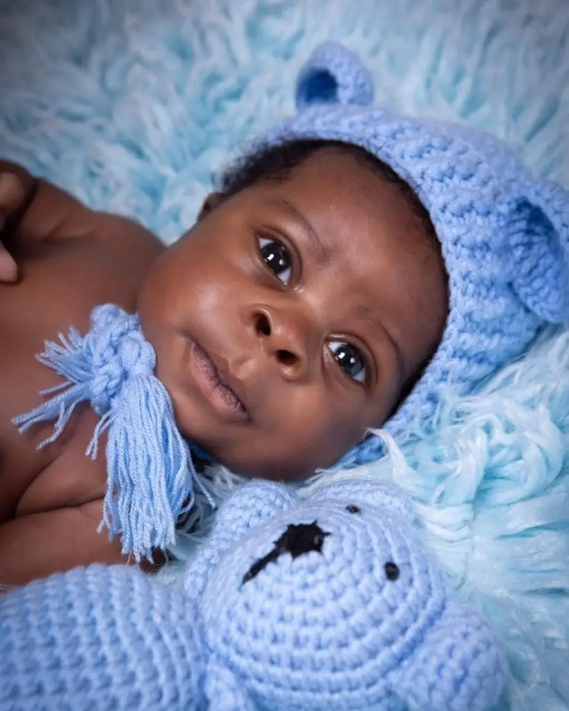 newborn baby close up portrait in Birmingham photography studio with blue knitted hat and teddy