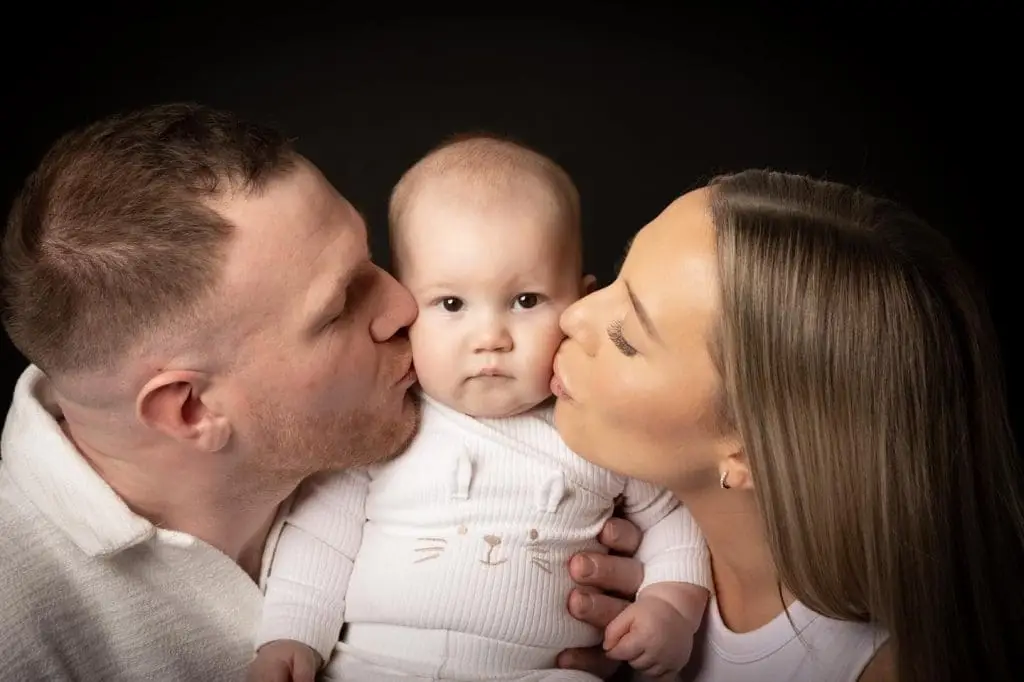 parents kissing baby during Birmingham family photoshoot in photography studio