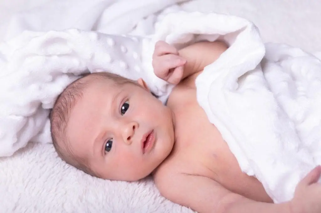 awake newborn baby portrait in Birmingham photography studio lying on soft white blanket