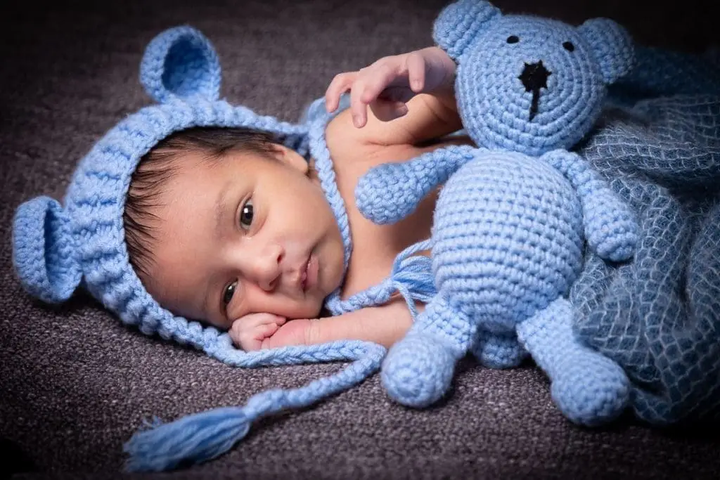 newborn baby portrait in Birmingham photography studio with blue knitted hat and teddy bear