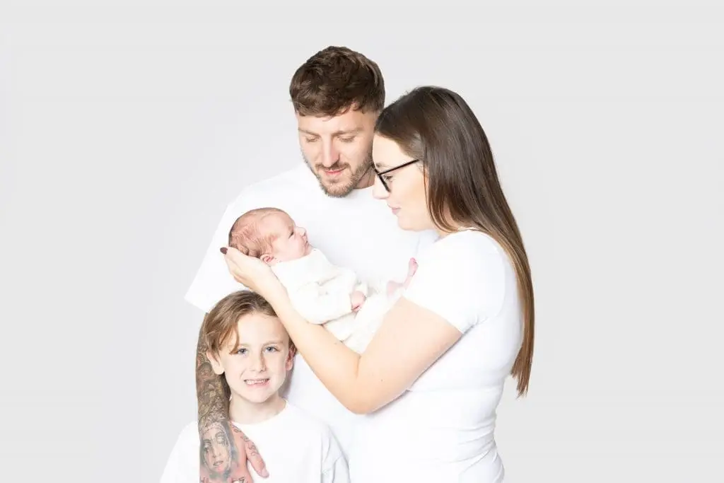 newborn baby with parents and older child during Birmingham newborn photography studio session