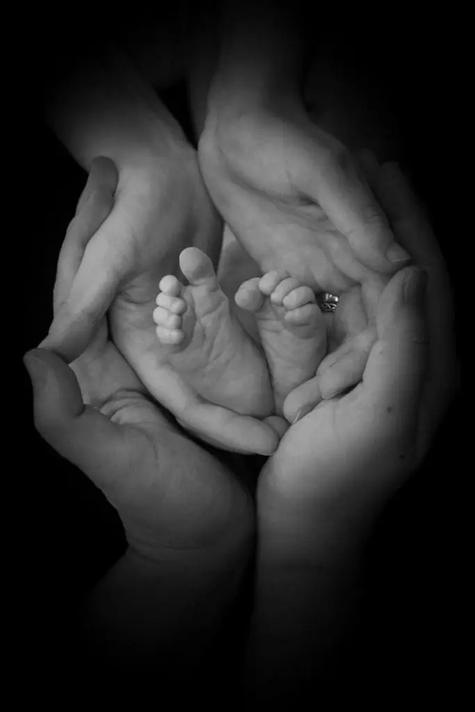 black and white newborn detail portrait in Birmingham photography studio with baby feet in parent hands