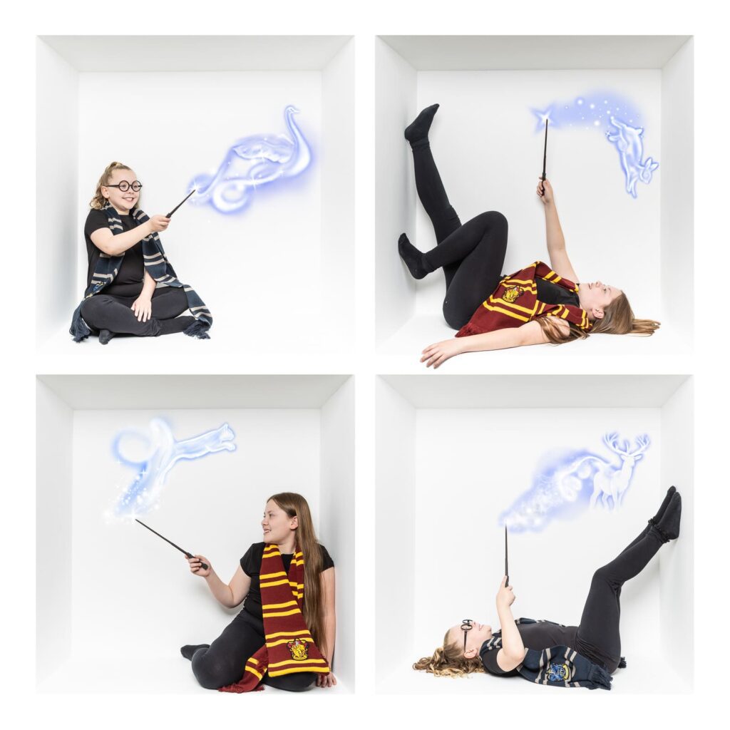 Four girls in Harry Potter costumes pose in white boxes, using wands to cast glowing blue spell shapes including animals and symbols, creating a magical and playful scene expertly captured by a Birmingham inside the box photographer.