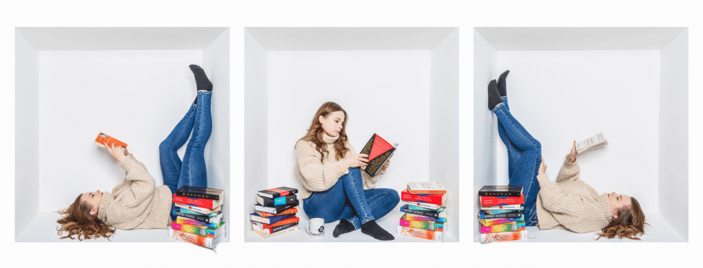 Three panels show a woman in a jumper and jeans, photographed by a Birmingham inside-the-box photographer, lying or sitting in a white box surrounded by stacks of books. She reads in different relaxed poses—legs up or crossed—with a coffee mug nearby.